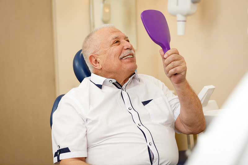 patient smiling with his new implant supported dentures