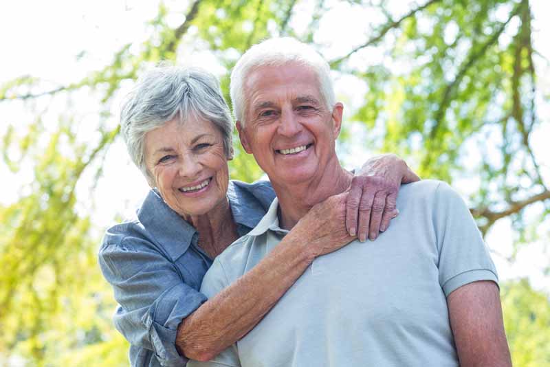 a couple smiling with their newly placed dental implants