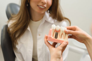 Dental Patient Getting Shown A Dental Implant Model During Her Consultation