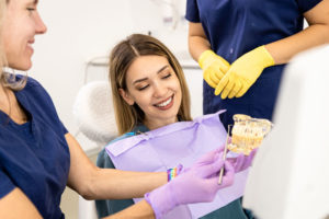 a zirconia dental implants patient smiling being shown an implant model.