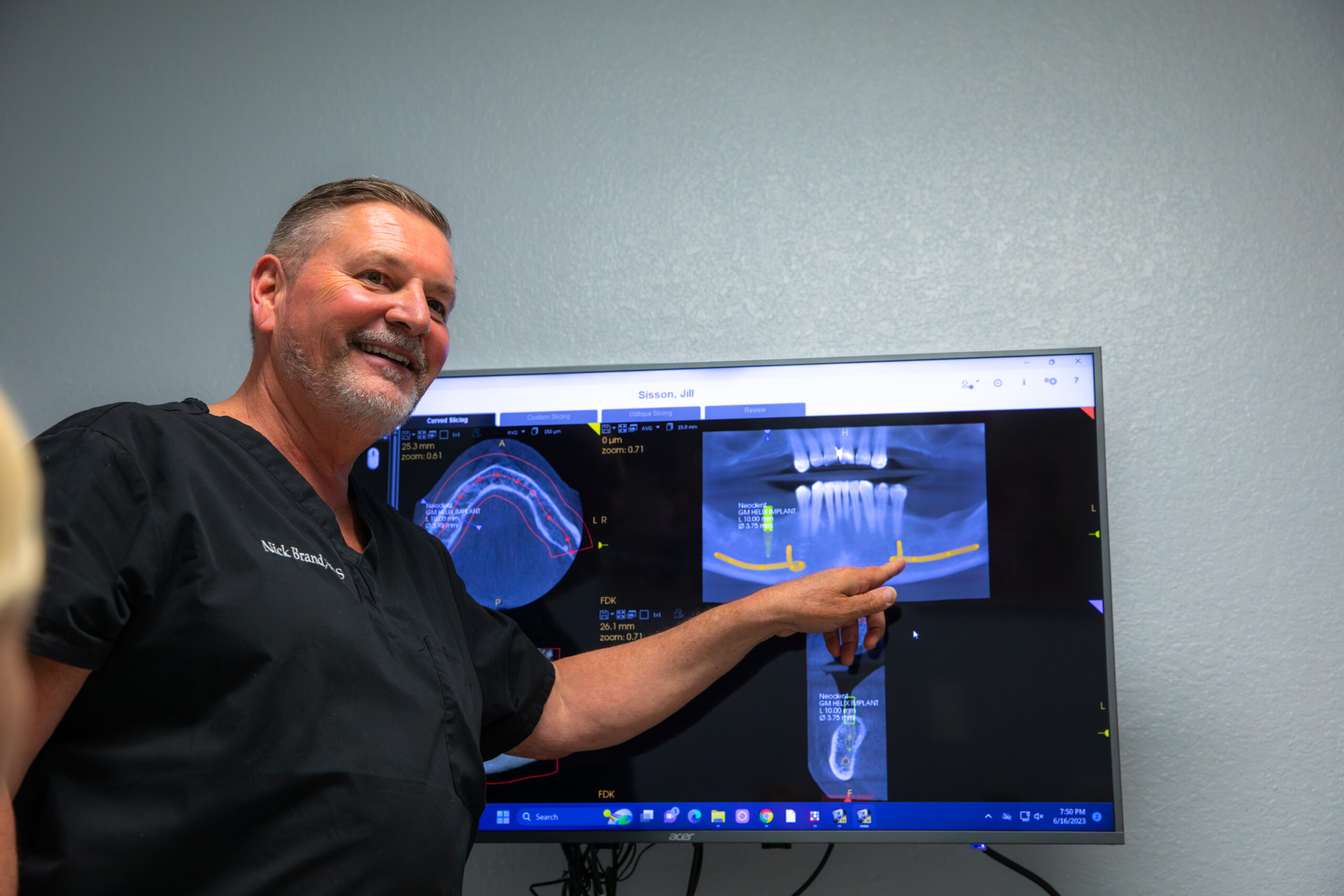 Dr. Brand smiling and pointing at a patients x-ray before their bone grafting procedure begins.