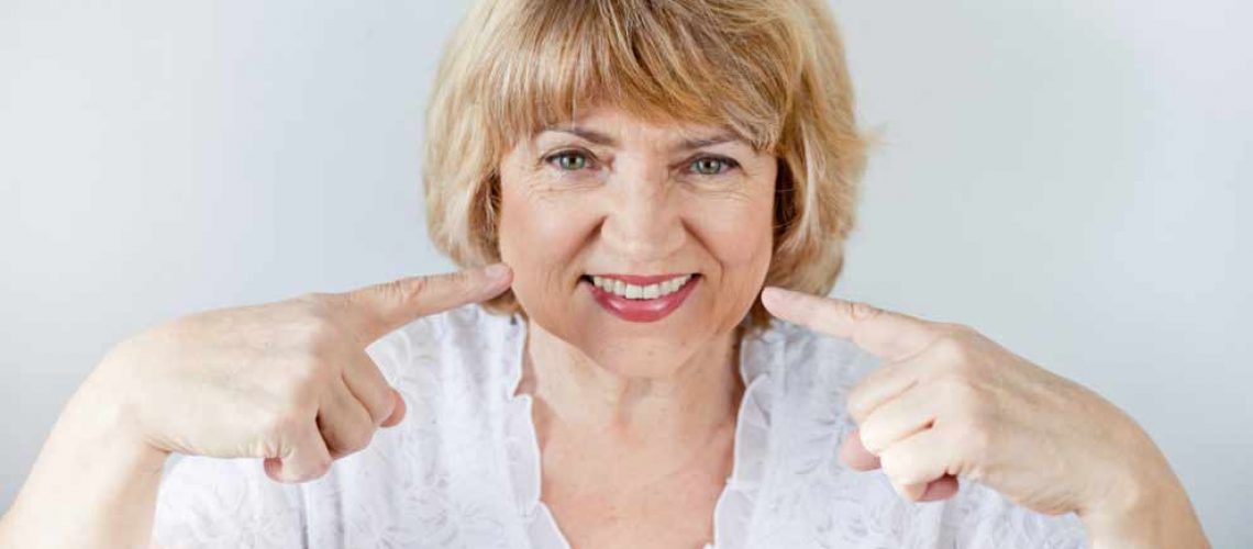 a patient smiling after getting a denture stabilization treatment